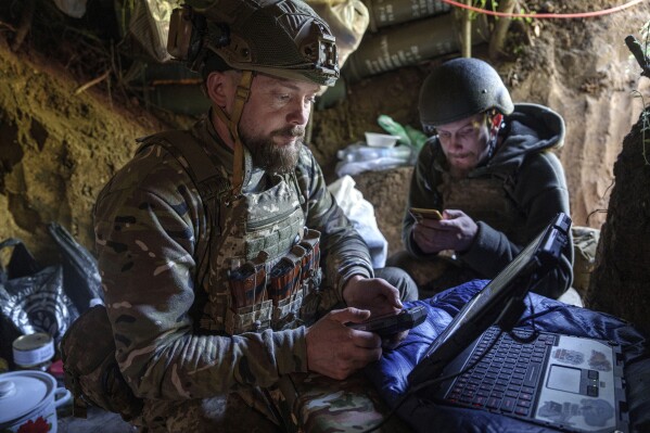 Ukrainian serviceman Andrii, left, of the Air Assault Forces 148th separate artillery brigade, sends receiving coordinates for a Furia drone at the frontline in Donetsk region, Ukraine, Thursday May 9, 2024. (AP Photo/Evgeniy Maloletka)