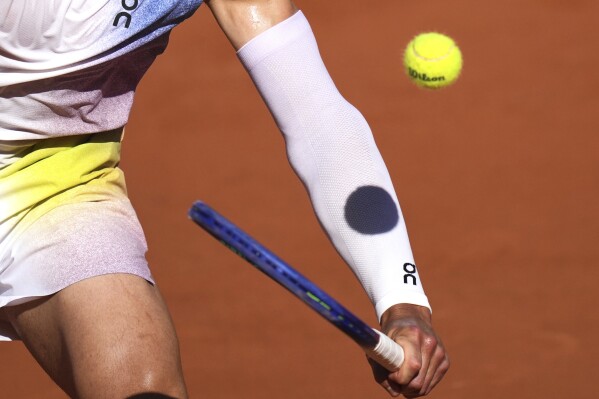 A ball casts its shadow on the arm of Ben Shelton of the U.S. as he plays Italy's Matteo Gigante , during their third round match of the French Tennis Open, at the Roland-Garros stadium, in Paris, Friday, May 30, 2025. (AP Photo/Thibault Camus)