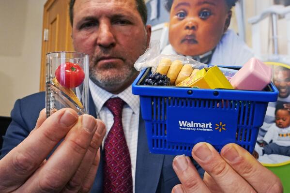 James A Swartz, Director of the Boston-based group World Against Toys Causing Harm Inc., holds up a tiny children's Walmart shopping basket toy, which they deemed a choking hazard, and a choking test gauge, at left, after unveiling the group's nominees for the "10 Worst Toys" at Franciscan Children's hospital, Wednesday, Nov. 17, 2021, in Boston. Toys with tiny accessories children can choke on, wheeled toys that could lead to falls, and toys that fire projectiles that could possibly injure a child's eyes are among the playthings on an annual list released Wednesday by a consumer safety advocacy group. This holiday shopping season, the group urged parents to be particularly vigilant as supply chain issues may cause shortages of some toys, prompting parents to look to alternative sources for purchases. (AP Photo/Charles Krupa)