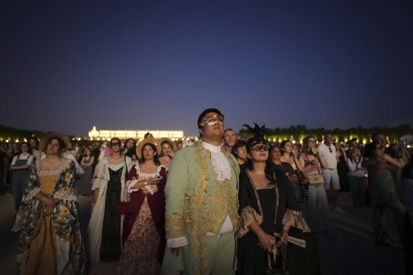 Costumed guests watch fireworks in the gardens of the Versailles castle before the Great Masked Ball in Versailles, outside Paris, Saturday, June 21, 2025. (AP Photo/Christophe Ena)