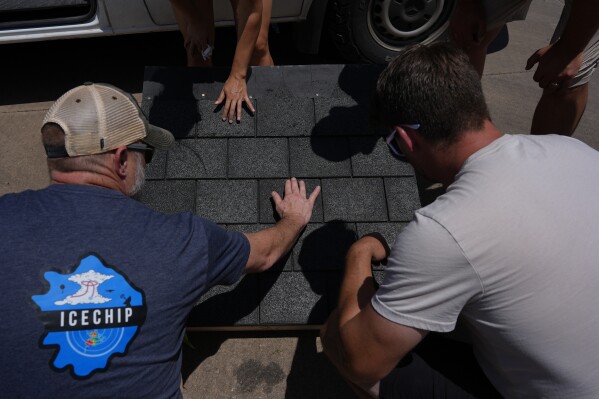Members of Project ICECHIP inspect shingles for hail damage during an operation Friday, June 6, 2025, in Morton, Texas. (AP Photo/Carolyn Kaster)