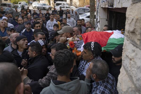 Palestinian mourners carry the body of Daoud Mahmoud Khalil Rayan, 42, during his funeral in the West Bank village of Beit Duqqu, southwest of Ramallah, Thursday, Nov. 3, 2022. The Palestinian Health Ministry said that Rayan was killed by Israeli fire in the occupied West Bank. Israeli police said it happened during a raid in the territory and alleged the man threw a firebomb at the forces. (AP Photo/Nasser Nasser)