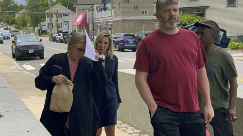 Denise Lodge, left, covers her face with a printout of the indictment against her as she walks from the federal courthouse, Wednesday, June 14, 2023, in Concord, N.H., following her arrest on charges related to an alleged scheme to steal and sell donated body parts. (Steven Porter/The Boston Globe via AP)