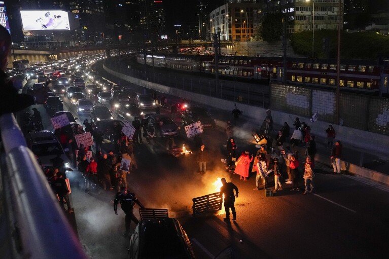 People block a highway during a protest to demand the release of hostages taken to the Gaza Strip by Hamas militants during the Oct. 7 attack, in Tel Aviv, Israel, Saturday, Feb. 10, 2024. (AP Photo/Ariel Schalit)