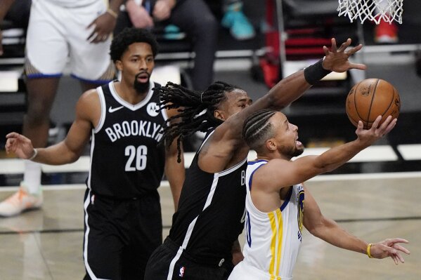 Brooklyn Nets guard Spencer Dinwiddie (26) watchs as Nets center DeAndre Jordan (6) defends Golden State Warriors guard Stephen Curry (30) during the first quarter of an opening night NBA basketball game, Tuesday, Dec. 22, 2020, in New York. (AP Photo/Kathy Willens)