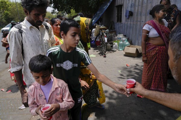 FILE - Passersby stand in a queue to receive a cup of cold drink distributed by an organization as a heat wave grips the Indian capital New Delhi, India, May 30, 2024. Month after month, global temperatures are setting new records. (AP Photo/Manish Swarup, File)