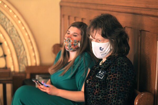 In this photo from Thursday, April 8, 2021, Jeanne Gawdun, right, a lobbyist for Kansans for Life, the most influential anti-abortion group in Kansas politics, watches as the state Senate debates a bill that would limit how many absentee ballots a person can collect and deliver for voters, at the Statehouse in Topeka, Kan. She says Kansans for Life backs the bill because it is concerned that abortion providers and their allies will use the tactic to collect ballots and defeat a proposed anti-abortion initiative on the ballot in the state's August 2022 primary. (AP Photo/John Hanna)