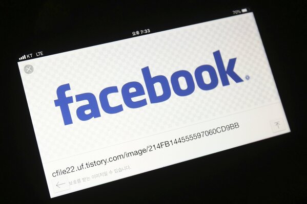FILE - In this Wednesday, March 21, 2018 file photo, the Facebook logo is seen on a smartphone in Ilsan, South Korea. Facebook has started testing a tool that lets users move their images more easily to other online services, as it faces pressure from regulators to loosen its grip on data. The social network said Monday, Dec. 2, 2019 the new tool will allow people to transfer their photos and videos to other platforms, starting with Google Photos. (AP Photo/Ahn Young-joon)