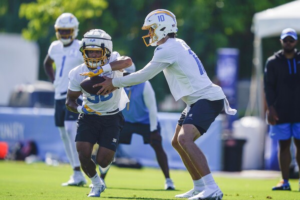 Los Angeles Chargers quarterback Justin Herbert hands off the ball to running back Austin Ekeler during the NFL team's training camp, Wednesday, July 26, 2023, in Costa Mesa, Calif. (AP Photo/Ryan Sun)