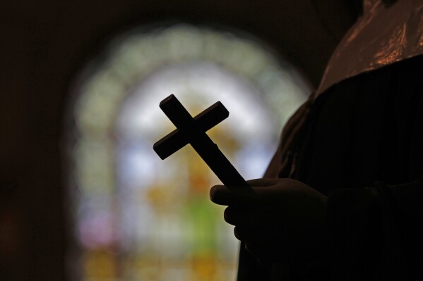 FILE - This Dec. 1, 2012 file photo shows a silhouette of a crucifix and a stained glass window inside a Catholic Church in New Orleans. In April 2024, Louisiana State Police carried out a sweeping search warrant at the Archdiocese of New Orleans, seeking a long-secreted cache of church records and communications between local church leaders and the Vatican about the church's handling of clergy sexual abuse. (AP Photo/Gerald Herbert, File)