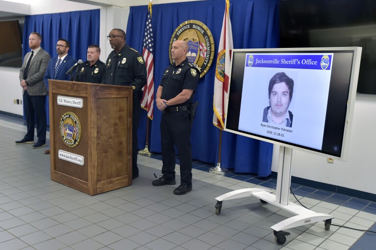 FILE - A photograph of shooter Ryan Christopher Palmeter is shown on a video monitor during Sheriff T.K. Waters' press conference at the Jacksonville Sheriff's Office headquarters building in Jacksonville, Fla., Sunday, Aug, 27, 20123. Waters is flanked by, from left, homicide detective Derek Kelsay, homicide Lt. Adam Blinn, Deputy Adam Parker and the director of Investigations Mark Romano. (Bob Self/The Florida Times-Union via AP, File)