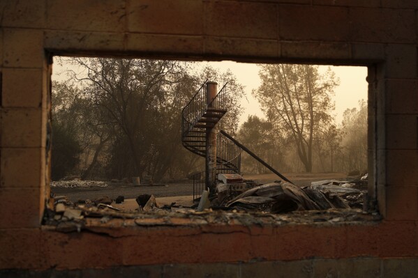 FILE - A spiral staircase stands in the remains of a burned out home from the Camp Fire, Nov. 10, 2018, in Paradise, Calif. With a housing crisis that has priced out many Native Hawaiians as well as families that have been there for decades, concerns are rising that Maui could become the latest example of “climate gentrification,” when it becomes harder for local people to afford housing in safer areas after a climate-amped disaster. Other examples include New Orleans after Hurricane Katrina in 2005 and Paradise, Calif., after the 2018 Camp Fire. (AP Photo/John Locher, File)