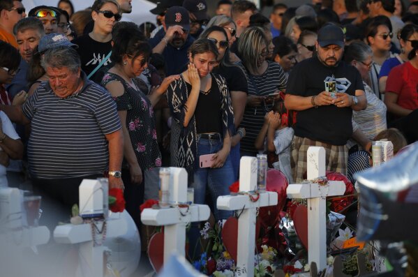 People visit a makeshift memorial at the scene of a mass shooting at a shopping complex, Tuesday, Aug. 6, 2019, in El Paso, Texas. (AP Photo/John Locher)