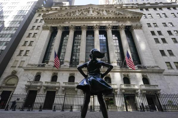 FILE - In this March 23, 2021 file photo, the Fearless Girl statue stands in front of the New York Stock Exchange in New York's Financial District. The global economic rebound from the pandemic has picked up speed but remains uneven across countries and faces multiple headwinds including the lack of vaccines in poorer nations. That could lead to new virus variants and more stop-and-go lockdowns, the Organization for Economic Cooperation and Development, OECD said in its latest forecast. (AP Photo/Mary Altaffer, File)