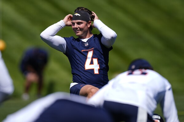 Denver Broncos quarterback Zach Wilson adjusts his headband while stretching before practice at the NFL football team's training headquarters Thursday, May 23, 2024, in Centennial, Colo. (AP Photo/David Zalubowski)