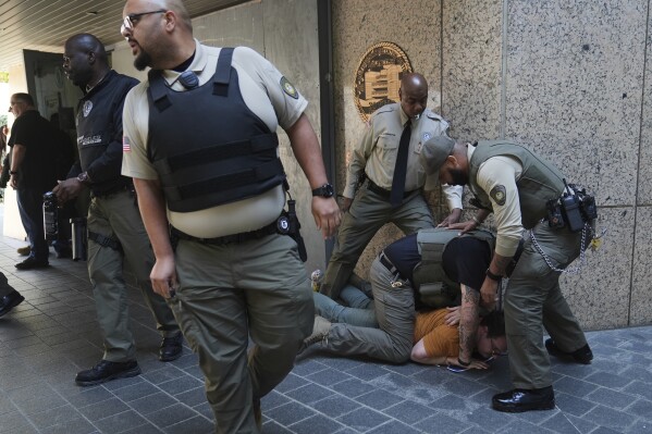 Law enforcement detain a protester at the U.S. Department of Justice Federal Bureau of Prisons after federal immigration authorities conducted an operation on Friday, June 6, 2025, in Los Angeles. (AP Photo/Jae C. Hong)
