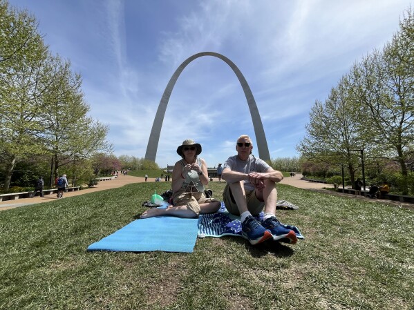 Colleen Devine (left), 63, and her husband Mark, 64, sit on the lawn near the Gateway Arch in St. Louis to watch the eclipse on April 8. (AP Photo/Michael Phillis)