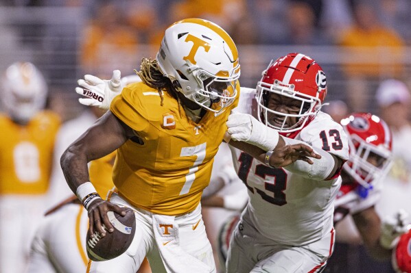 Tennessee quarterback Joe Milton III (7) is chased by Georgia defensive lineman Mykel Williams (13) during the second half of an NCAA college football game Saturday, Nov. 18, 2023, in Knoxville, Tenn. (AP Photo/Wade Payne)