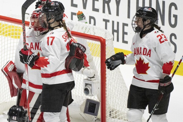 Canada goaltender Emerance Maschmeyer, left, celebrates with teammates Ella Shelton (17) and Erin Ambrose (23) following their win over Switzerland at the IIHF Women's World Hockey Championship in Utica, N.Y., Friday, April 5, 2024. (Christinne Muschi/The Canadian Press via AP)