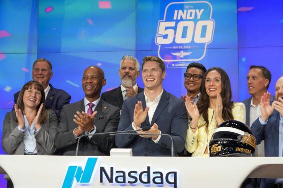 Josef Newgarden, second from right, is joined by his wife Ashley, right, as he rings the opening bell at the Nasdaq MarketSite, Tuesday, May 30, 2023, in New York. Newgarden won the 107th running of the Indianapolis 500 auto race Sunday. (AP Photo/Mary Altaffer)