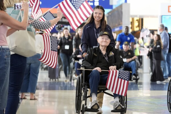 World War II veteran Martin Sylvester is helped along at Dallas Fort Worth International Airport in Dallas Friday, May 31, 2024. A group of World War II veterans are being flown from Texas to France where they will take part in ceremonies marking the 80th anniversary of D-Day. (AP Photo/LM Otero)