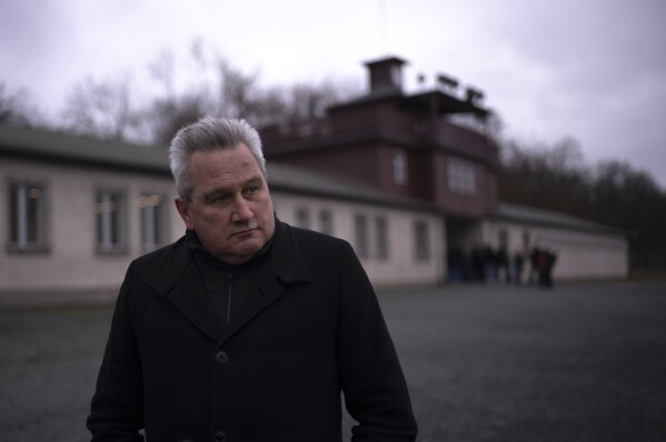 The head of the Buchenwald Memorial, Jens-Christian Wagner poses for a photo near the main gate of the former Nazi concentration camp Buchenwald in Weimar, Germany, Wednesday, Jan. 31, 2024. Attacks on the site have stepped up massively in recent months: Wagner says this is because of the "revisionist, antisemitic and racist slogans" promoted by the far-right Alternative for Germany, or AfD party. (AP Photo/Markus Schreiber)