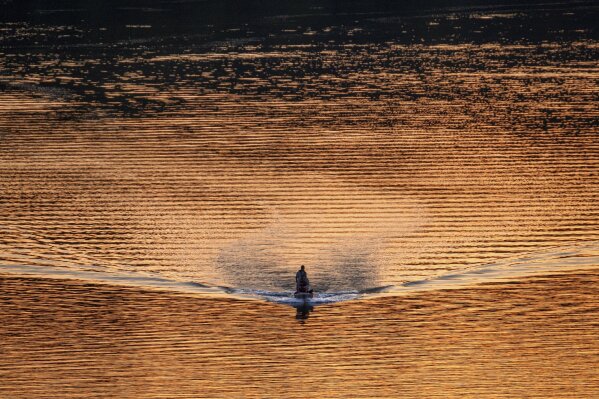 A single bass fishing boat cruises along the Potomac River at sunset in Washington, Wednesday evening, April 8, 2020. Boat traffic on the river is thinner than usual as people practice social distancing during the coronavirus outbreak. (AP Photo/J. David Ake)