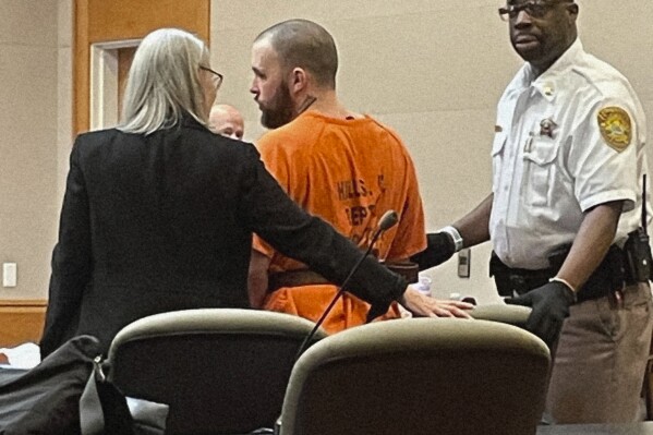 Adam Montgomery is led to the defense table for his sentencing hearing in Hillsborough County Superior Court in Manchester, N.H. on Monday, Aug. 7, 2023. The New Hampshire father charged in the murder of his missing 5-year-old daughter Harmony Montgomery used the court hearing on unrelated gun charges to proclaim his innocence. Montgomery, 33, was found guilty of six gun charges in June was in court to be sentenced for those crimes. (Paul Feely/Union Leader via AP)