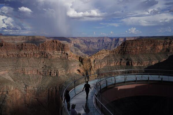People walk across the Grand Canyon Skywalk on Hualapai reservation Tuesday, Aug. 16, 2022, in northwestern Arizona. Roughly 600,000 tourists a year visit the Grand Canyon on the Hualapai reservation in northwestern Arizona — an operation that's the tribe's main source of revenue. (AP Photo/John Locher)