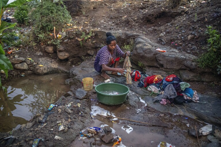 Rekha Wagh washes clothes early in the morning by a sewer near Shahapur, northeast of Mumbai, India, Saturday, May 6, 2023. (AP Photo/Dar Yasin)