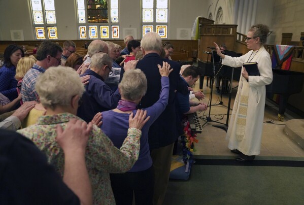The Rev. Tracy Cox of First United Methodist Church and members of her congregation pray for Tracy Merrick, who will attend the United Methodist General Conference as a delegate representing Western Pennsylvania, as well as Anais Hussian and Joshua Popson who will also be in attendance, Sunday, April 14, 2024, in Pittsburgh. Hussian is a reserve delegate and Popson will be advocating for LGBTQ inclusion with the Love Your Neighbor Coalition. Many, including Rev. Cox, hope that this is the year they change longstanding bans on LGBTQ clergy and same-sex marriage. (AP Photo/Jessie Wardarski)