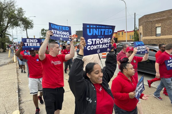 United Auto Workers members march while holding signs at a union rally held near a Stellantis factory Wednesday, Aug. 23, 2023, in Detroit. UAW President Shawn Fain told reporters that bargaining on a new contract is not going well between the UAW and Detroit's three automakers. (AP Photo/Mike Householder)