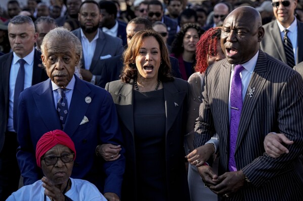 The Rev. Al Sharpton, Vice President Kamala Harris and Attorney Ben Crump walk and sing across the Edmund Pettus Bridge with others commemorating the 59th anniversary of the Bloody Sunday voting rights march in 1965, Sunday, March 3, 2024, in Selma, Ala. (AP Photo/Mike Stewart)