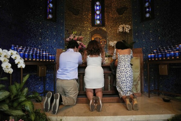 People kneel in prayer at Madonna della Strada Chapel at Loyola University Chicago shortly before Chicago-born Robert Francis Cardinal Prevost was announced as Pope Leo XIV, Thursday, May 8, 2025, in Chicago. (AP Photo/Erin Hooley)