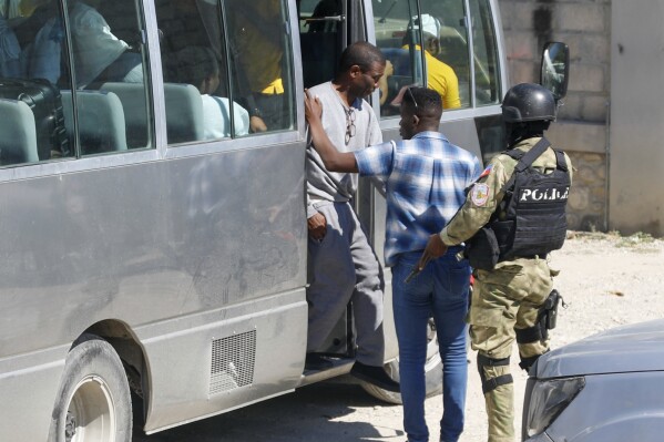 FILE - Former coup leader Guy Philippe, wearing a gray sweatsuit, descends from a bus at Haiti's National Police station, in Port-au-Prince, Nov. 30, 2023, after he was repatriated from the U.S. Supporters of Philippe launched protests on Monday, Jan. 15, 2024, that have paralyzed some cities across Haiti as they demand the resignation of Prime Minister Ariel Henry. (AP Photo/Odelyn Joseph, File)