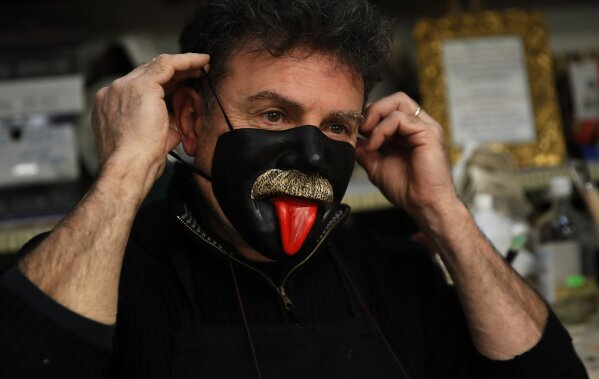 Venetian artisan carnival mask maker Gualtiero Dall'Osto wears one of his creations in his workshop in Venice, Italy, Saturday, Jan. 30, 2021. (AP Photo/Antonio Calanni)