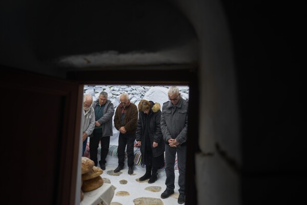 Os fiéis ficam do lado de fora da capela de Panagia Evangelistria, na ilha de Amorgos, Grécia, enquanto o monge cristão ortodoxo Padre Spyridon de Amorgos conduz a Divina Liturgia, na terça-feira, 25 de março de 2025. (Foto AP/Petros Giannakouris)