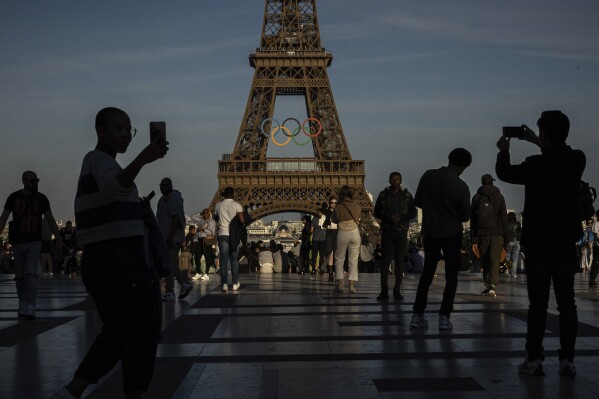 People photograph and film the Olympic rings that are displayed on the Eiffel Tower Friday, June 7, 2024 in Paris. (AP Photo/Aurelien Morissard)