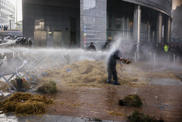 FILE - Riot police use water to disperse farmers during a protest by farmers in front of the European Parliament as European leaders attend an EU summit in Brussels on Thursday, February 1, 2024.  (AP Photo/Thomas Padilla, File)