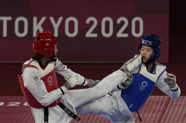 Kimia Alizadeh Zonoozi, Refugee Olympic Team, left, attacks China's Zhou Lijun during the taekwondo women's 57kg match at the 2020 Summer Olympics, Sunday, July 25, 2021, in Tokyo, Japan. (AP Photo/Themba Hadebe)