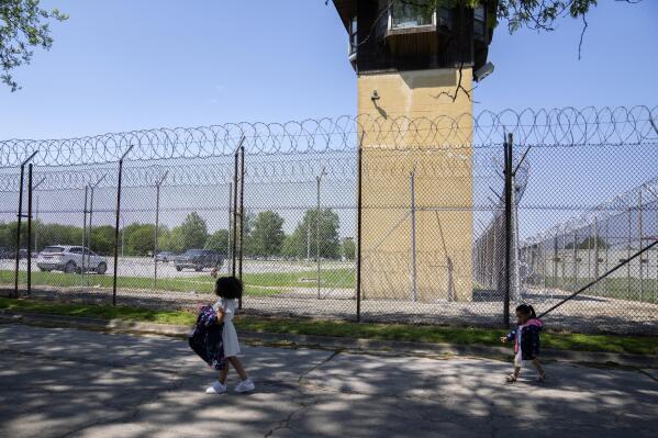 Myla Martinez, 6, left, and her sister Jaliyah Santiago, 4, pass by a guard tower as they leave Logan Correctional Center after visiting their mother Crystal Martinez, Saturday, May 20, 2023, in Lincoln, Illinois. Rare programs like the Reunification Ride, a donation-dependent initiative that buses prisoners' family members from Chicago to Illinois' largest women's prison every month so they can spend time with their mothers and grandmothers, are a crucial lifeline for families, prisoners say. (AP Photo/Erin Hooley)