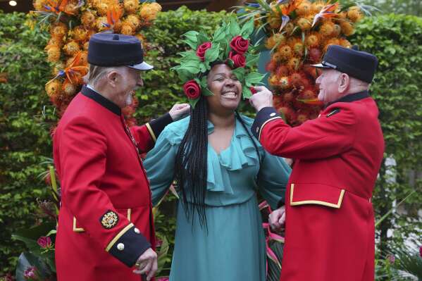 Chelsea Pensioners Jack McCabe, left, and Tony Manley, right, look at the hat worn by Claire Myers-Lamptey designed by Mathew Eluwande for Nature Recovery, for communities to embrace re-wilding at the RHS Chelsea Flower Show in London, Monday, May 19, 2025. (AP Photo/Kirsty Wigglesworth)