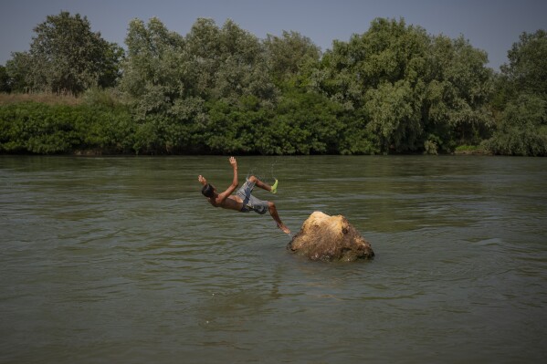 Youngsters cool off in the river Arges, outside Bucharest, Romania, Wednesday, July 12, 2023. (AP Photo/Vadim Ghirda)