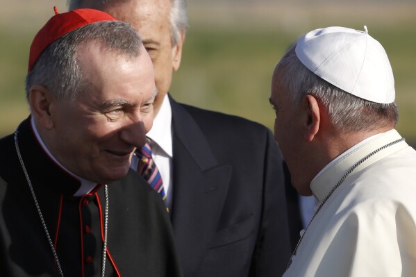 FILE - Pope Francis greets Vatican Secretary of State Monsignor Pietro Parolin, left, as he arrives to board a plane to Amman, Jordan, for a three-day trip to the Middle East including the West Bank and Israel, at Rome's Fiumicino international airport, Saturday, May 24, 2014. The Vatican secretary of state is trying to defuse Pope Francis' latest diplomatic kerfluffle, insisting in media interviews that a primary condition for negotiations to end the war in Ukraine is an end to Russia’s aggression and that any peace must be a “just peace.” (AP Photo/Riccardo De Luca, File)