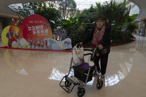 An elderly woman pushes her walker inside the giant atrium of Yan Garden, a high-end senior-focused community that opened in 2015 by insurance company Taikang Insurance Group in Beijing, Nov. 5, 2024. (AP Photo/Ng Han Guan)