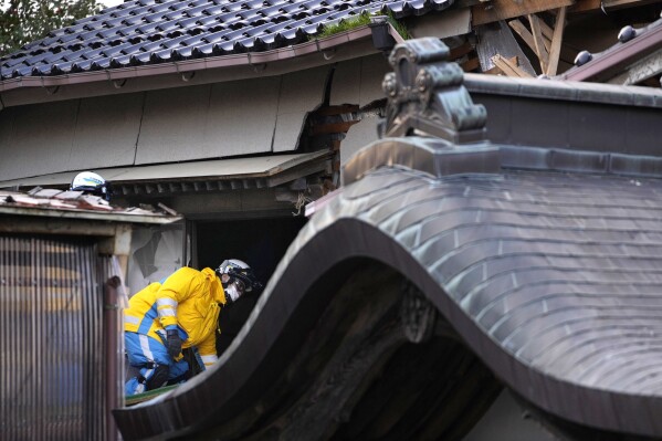 Police officers go into a building at the premises of a temple to search for victims in Wajima in the Noto peninsula, facing the Sea of Japan, northwest of Tokyo, Saturday, Jan. 6, 2024, following Monday's deadly earthquake. (AP Photo/Hiro Komae)