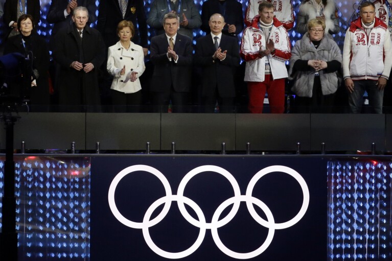 FILE - Anne Rogge, former International Olympic Committee (IOC) President Jacques Rogge, Claudia Bach, IOC President Thomas Bach and Russian President Vladimir Putin, from left, applaud at the closing ceremony of the 2014 Winter Olympics, in Sochi, Russia on Sunday, Feb. 23, 2014. When Russia hosted the Sochi Games, it sought to impress the world and expand its global clout with the most expensive Olympics ever. (AP Photo/Gregorio Borgia, File)