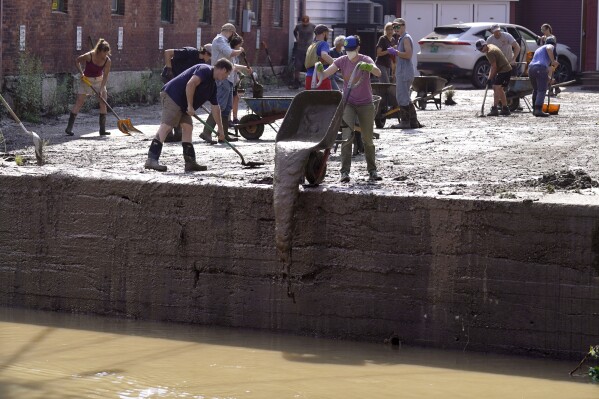  Volunteers clean up a downtown parking area on the banks of the Winooski River, July 12, 2023, in Montpelier, Vt. (AP Photo/Charles Krupa)