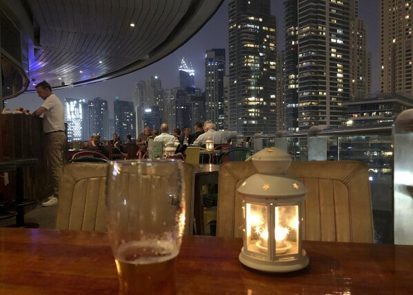 People enjoy drinking alcoholic beverages at a restaurant overlooking the Marina district in Dubai, United Arab Emirates, Wednesday, Oct. 23, 2019. Dubai has loosened its liquor laws to allow tourists to purchase alcohol in state-controlled stores, previously only accessible to license-holding residents, as the United Arab Emirates saw the first drop in alcohol sales by volume in a decade. (AP Photo/Kamran Jebreili)