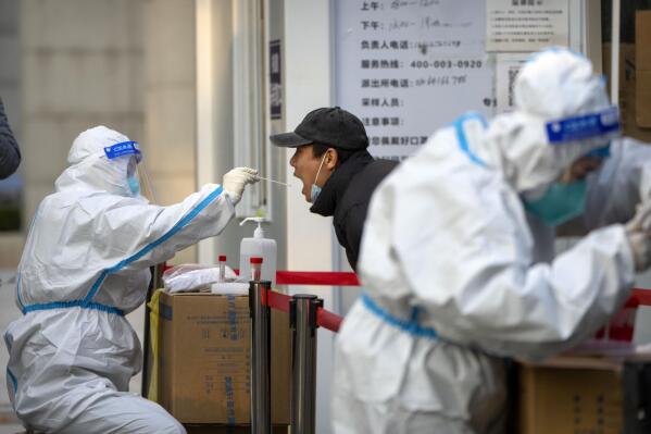 A worker wearing a protective suit swabs a man's throat for a COVID-19 test at a coronavirus testing site in Beijing, Thursday, Nov. 17, 2022. Chinese authorities faced more public anger Thursday after a second child's death was blamed on overzealous anti-virus enforcement, adding to frustration at controls that are confining millions of people to their homes and sparked fights with health workers. (AP Photo/Mark Schiefelbein)